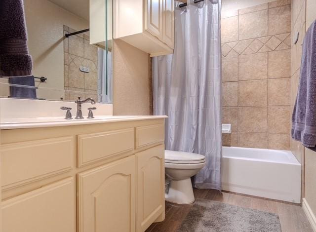 full bath with vanity, shower / bath combo with shower curtain, wood finished floors, and toilet