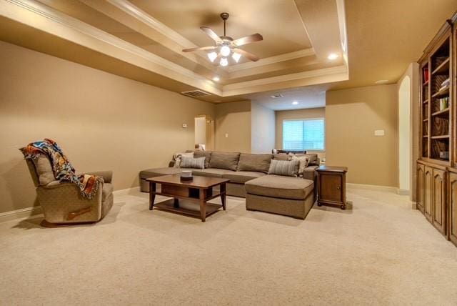 living room with light carpet, a tray ceiling, baseboards, and crown molding