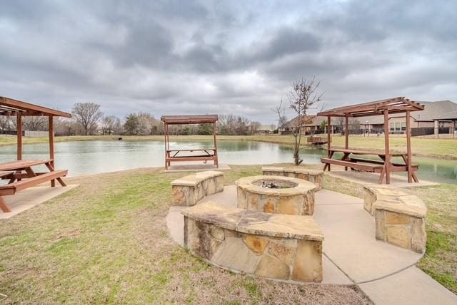 view of property's community featuring a fire pit, a yard, and a water view