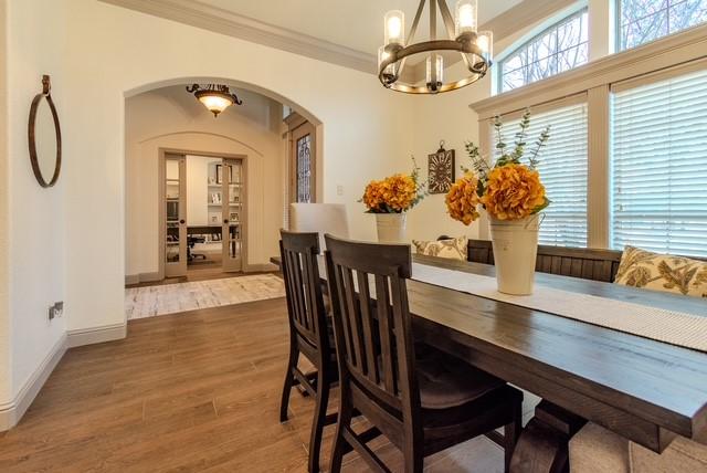 dining space featuring baseboards, arched walkways, ornamental molding, wood finished floors, and a chandelier