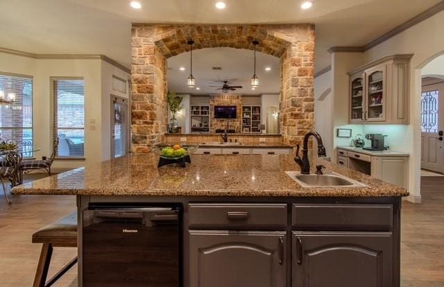 bar featuring arched walkways, ornamental molding, a sink, wood finished floors, and plenty of natural light