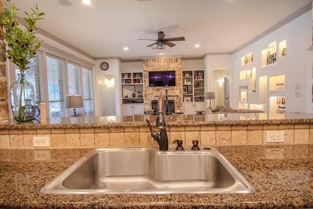 kitchen with stone counters, open floor plan, and ornamental molding