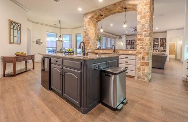 kitchen featuring beverage cooler, light wood-style floors, a sink, and crown molding