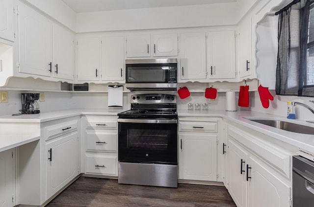 kitchen with dark wood-style floors, appliances with stainless steel finishes, white cabinets, and a sink