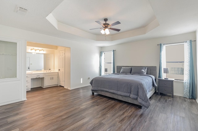 bedroom featuring baseboards, multiple windows, a tray ceiling, and dark wood-type flooring