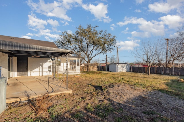 view of yard with a storage shed, a patio, an outbuilding, and fence