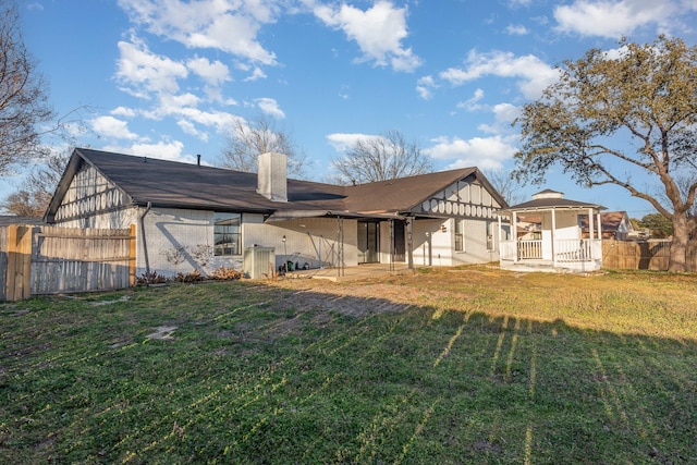 back of property with brick siding, a lawn, and fence