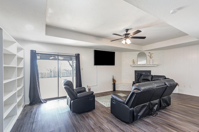 living area with a textured ceiling, a raised ceiling, and dark wood-type flooring