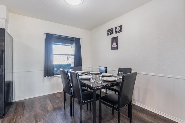 dining area featuring a wainscoted wall and wood finished floors