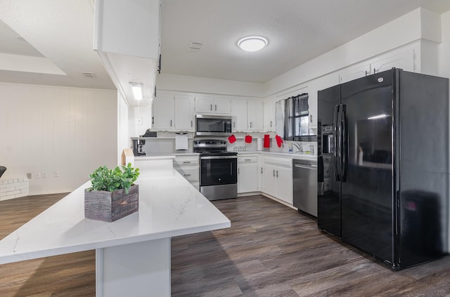 kitchen with stainless steel appliances, a peninsula, visible vents, white cabinetry, and dark wood finished floors