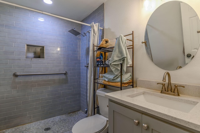 bathroom featuring toilet, a tile shower, and vanity