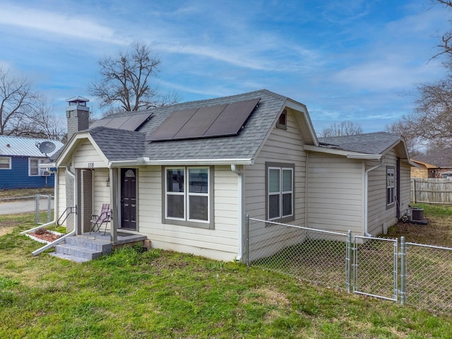 exterior space with a lawn, fence, a gate, and roof mounted solar panels