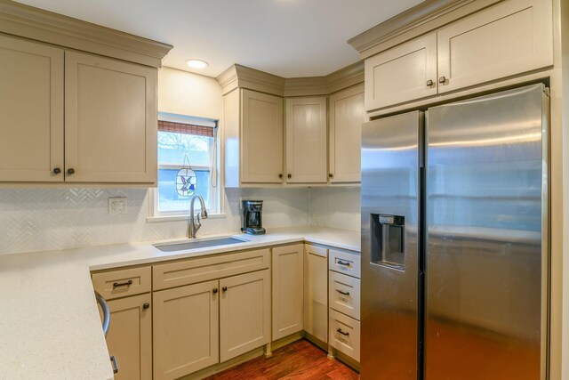 kitchen featuring dark wood-style flooring, a sink, light countertops, stainless steel fridge with ice dispenser, and tasteful backsplash