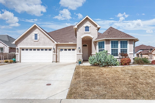 traditional-style home with a shingled roof, concrete driveway, an attached garage, and stucco siding