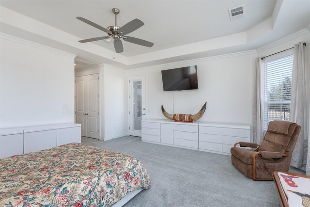 bedroom featuring a tray ceiling, crown molding, visible vents, light carpet, and ceiling fan