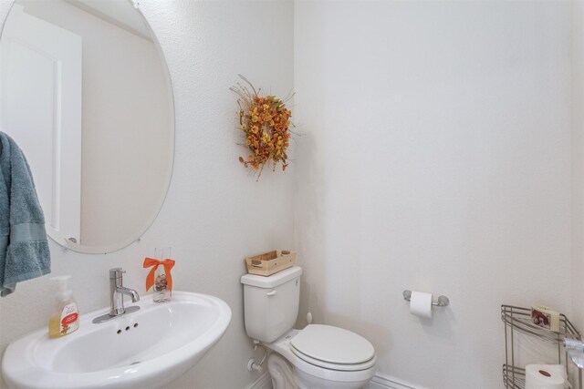 bathroom with toilet, baseboards, and a sink