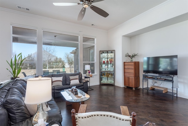 living area with baseboards, wood finished floors, visible vents, and crown molding