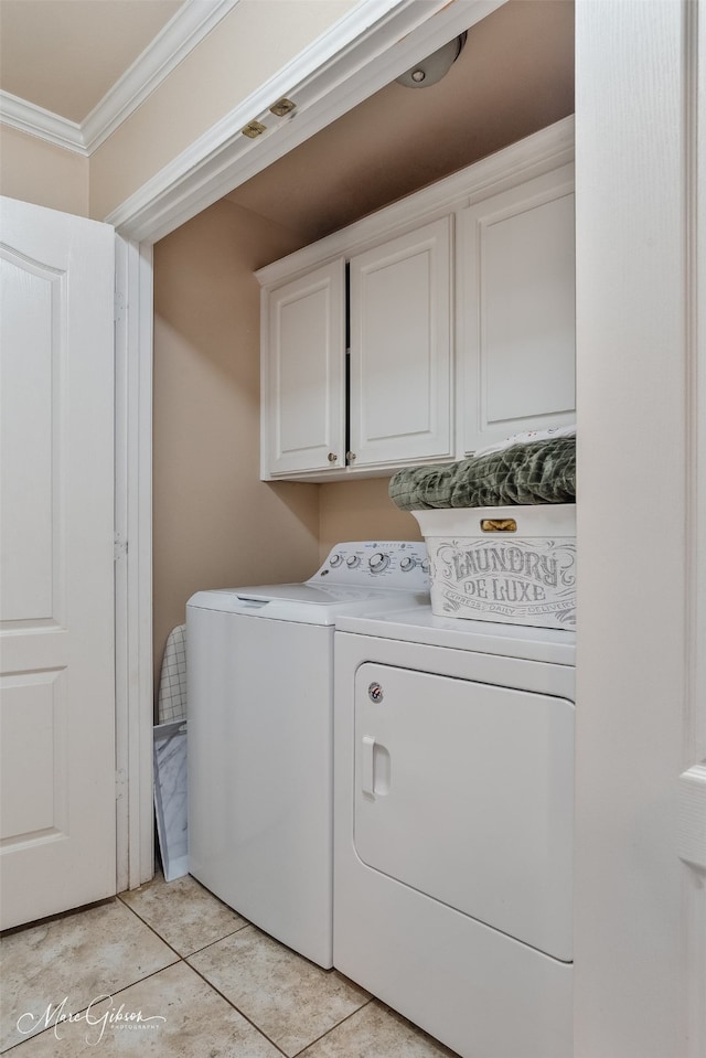 laundry area featuring ornamental molding, cabinet space, washer and clothes dryer, and light tile patterned floors