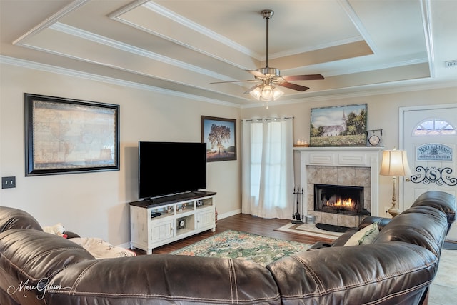 living area featuring visible vents, a ceiling fan, a tiled fireplace, wood finished floors, and a tray ceiling