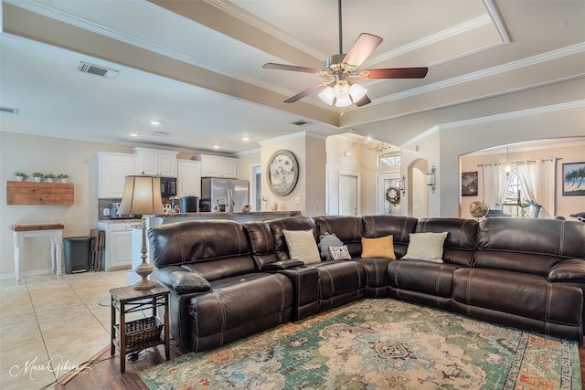 living room with light tile patterned floors, arched walkways, a raised ceiling, and visible vents