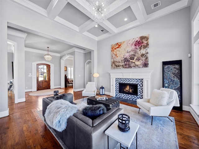 living area featuring baseboards, visible vents, arched walkways, wood finished floors, and a chandelier