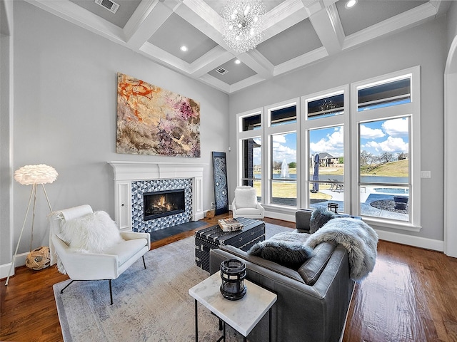 living room with a high ceiling, a tiled fireplace, wood finished floors, and baseboards