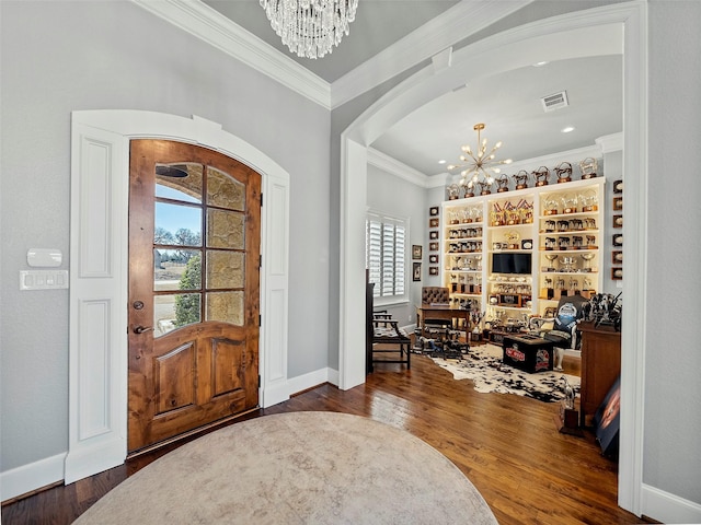 foyer entrance with crown molding, a notable chandelier, visible vents, wood finished floors, and baseboards