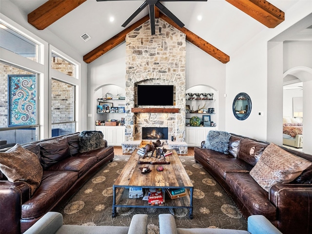 living room featuring visible vents, ceiling fan, a stone fireplace, high vaulted ceiling, and beamed ceiling