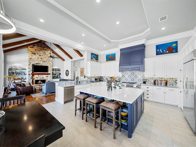 kitchen with stainless steel appliances, a peninsula, a fireplace, visible vents, and open floor plan