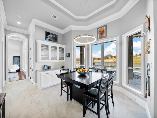 dining space featuring arched walkways, plenty of natural light, visible vents, and crown molding