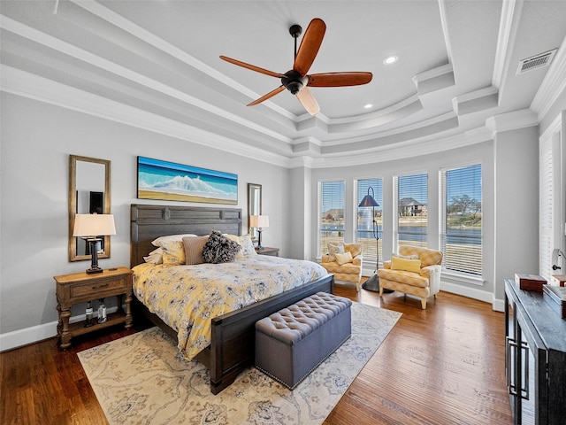 bedroom featuring baseboards, wood finished floors, a raised ceiling, and crown molding