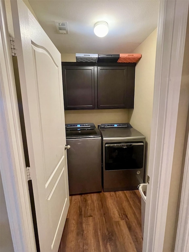 laundry room with visible vents, dark wood-style flooring, washer and clothes dryer, and cabinet space