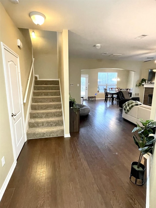 stairs featuring visible vents, a fireplace, baseboards, and wood finished floors