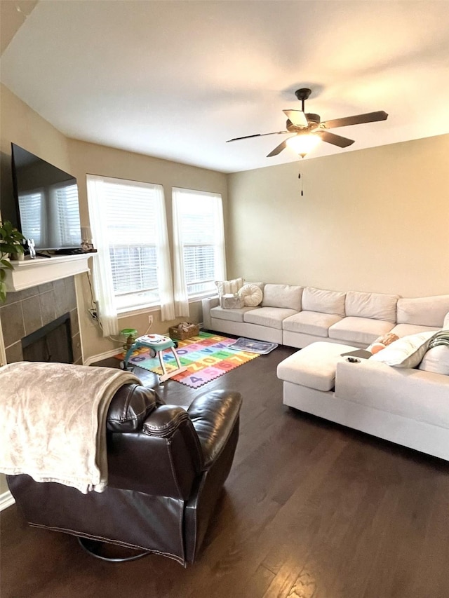 living room featuring ceiling fan, a fireplace, and wood finished floors