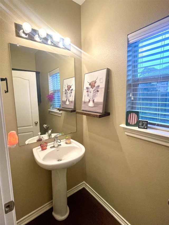 bathroom featuring plenty of natural light, baseboards, and a sink