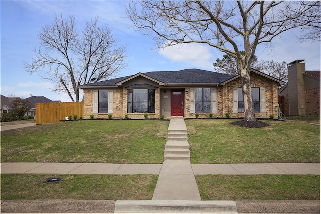 mid-century inspired home featuring a shingled roof, fence, a front lawn, and brick siding