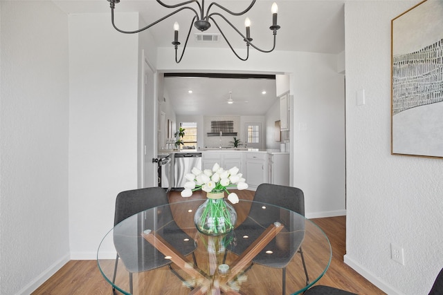 dining room featuring baseboards, visible vents, wood finished floors, and a textured wall