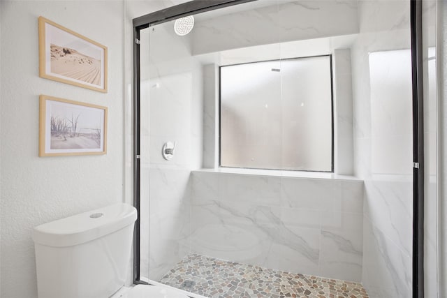 full bath featuring toilet and a marble finish shower