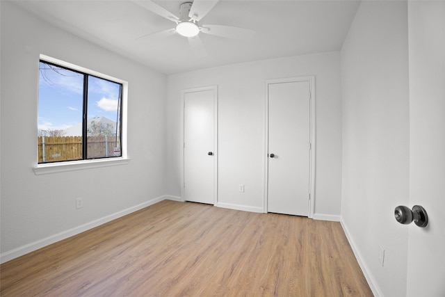 unfurnished bedroom with light wood-style flooring, baseboards, and a ceiling fan