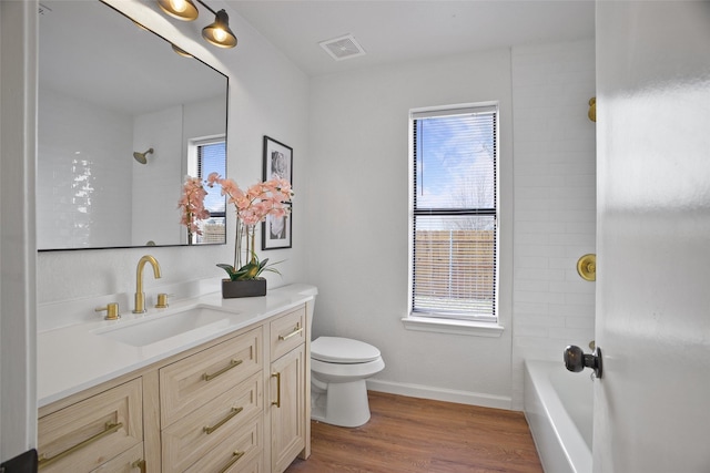 bathroom with toilet, wood finished floors, vanity, visible vents, and baseboards