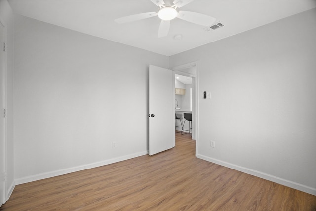 spare room with baseboards, visible vents, ceiling fan, and wood finished floors