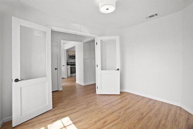 unfurnished room featuring light wood-style flooring, visible vents, and baseboards