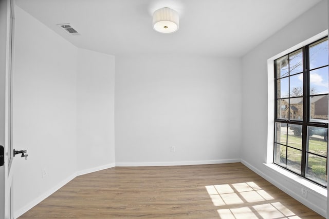 unfurnished room with light wood-type flooring, a wealth of natural light, and baseboards