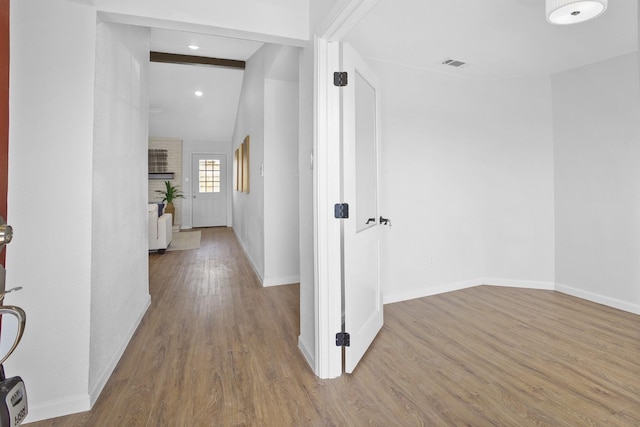 hall featuring visible vents, lofted ceiling with beams, baseboards, and wood finished floors