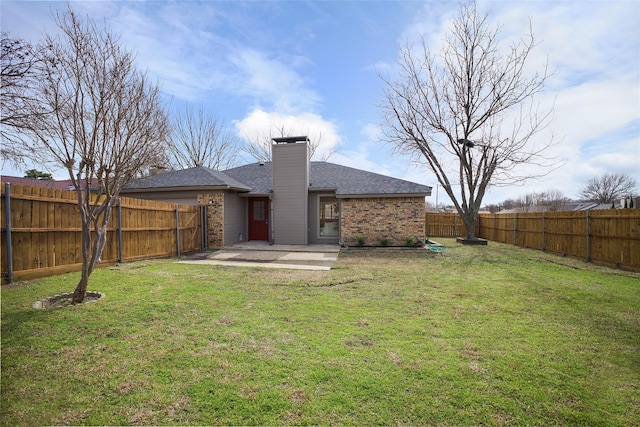 rear view of property featuring a yard, a fenced backyard, a patio, and a chimney