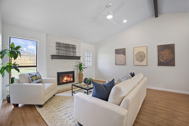 living area with a wealth of natural light, a brick fireplace, vaulted ceiling with beams, and wood finished floors