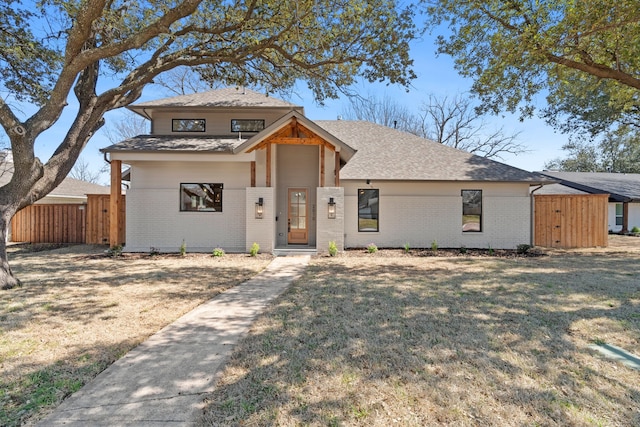 view of front facade with a front yard, brick siding, and fence