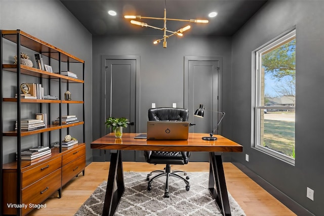 office area with light wood-style floors, baseboards, and a notable chandelier