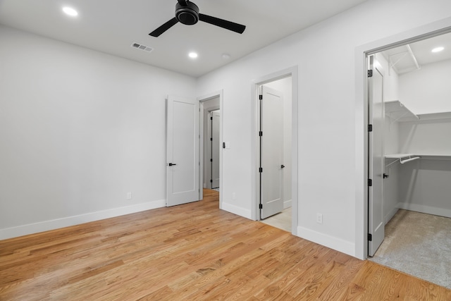 unfurnished bedroom with recessed lighting, light wood-style flooring, baseboards, and a spacious closet