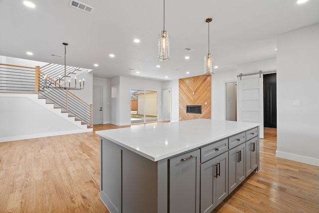 kitchen featuring gray cabinets, visible vents, light wood-style flooring, and a barn door